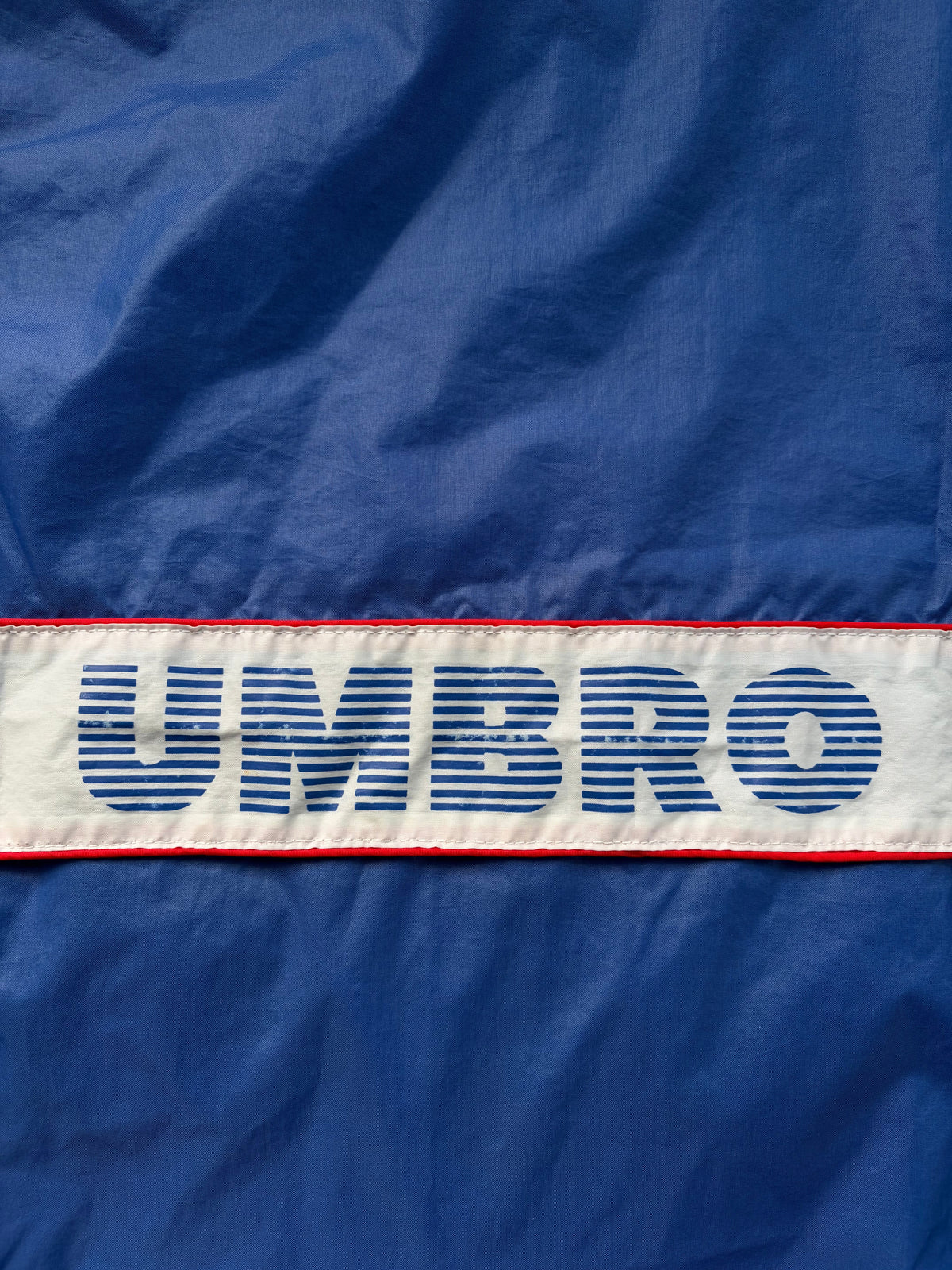 A blue and white Umbro windbreaker jacket shown from the back
