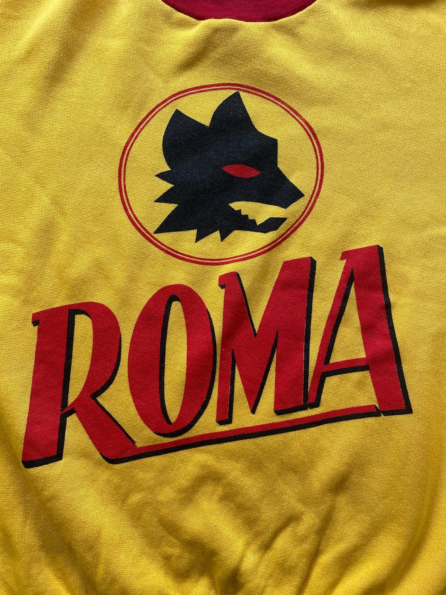 A yellow long-sleeve crewneck sweatshirt with red color-blocked sections on the sleeves and hem