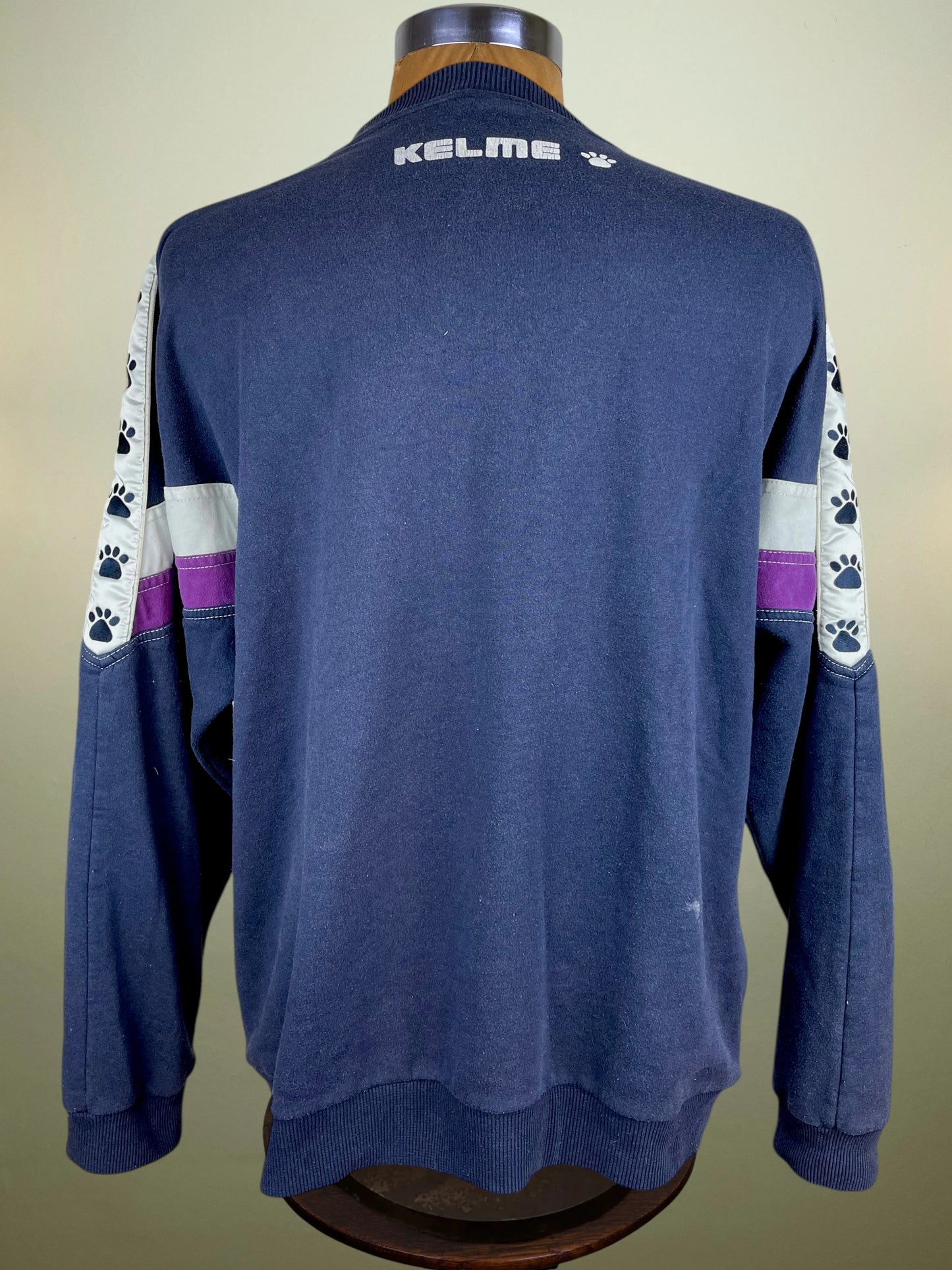 A navy blue long-sleeve sweatshirt with white and purple sleeve stripes and paw print details