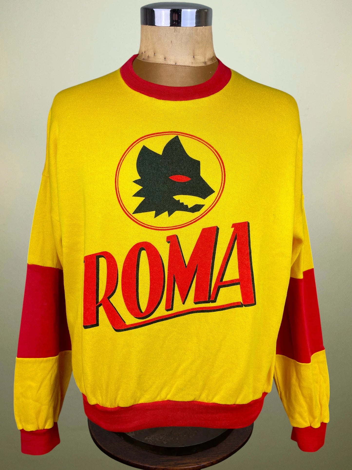 A yellow and red long-sleeve soccer sweatshirt with 'ROMA' and a wolf logo